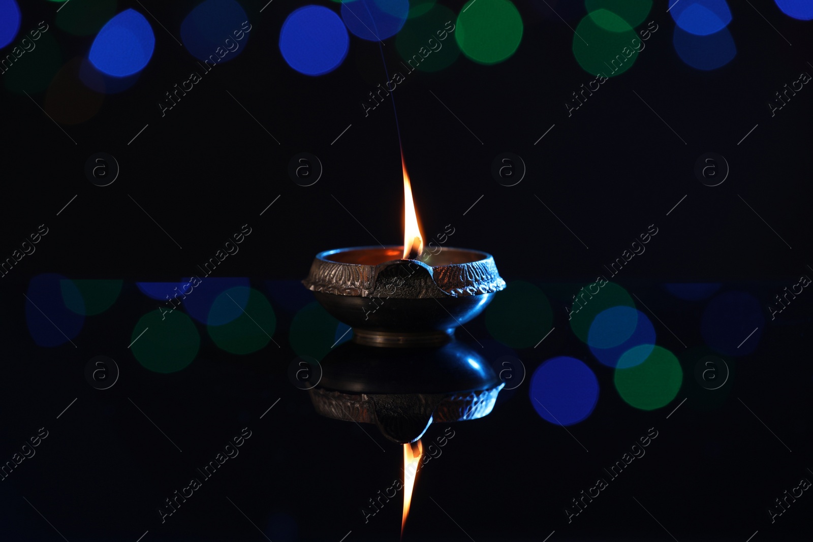 Photo of Lit diya on dark background with blurred lights. Diwali lamp