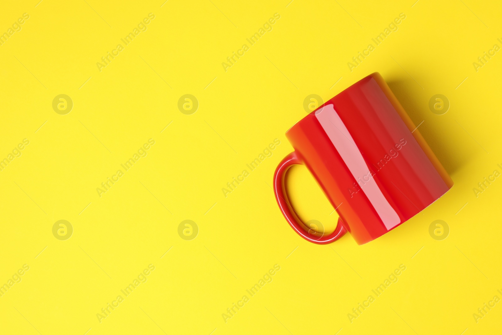 One red ceramic mug on yellow background, top view. Space for text Photo of One red ceramic mug on yellow background, top view. Space for text