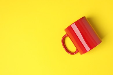 Photo of One red ceramic mug on yellow background, top view. Space for text
