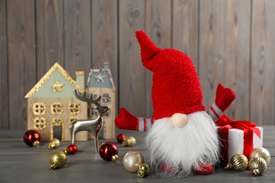 Photo of Cute Christmas gnome, gift boxes and festive decor on wooden table. Space for text