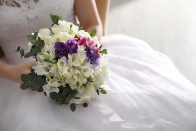 Photo of Bride holding beautiful bouquet with spring freesia flowers, closeup