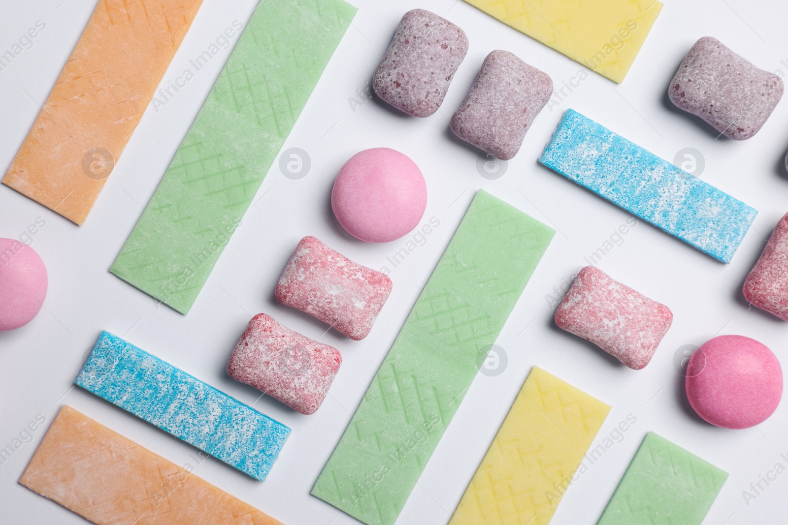 Photo of Different tasty colorful bubble gums on white background, flat lay