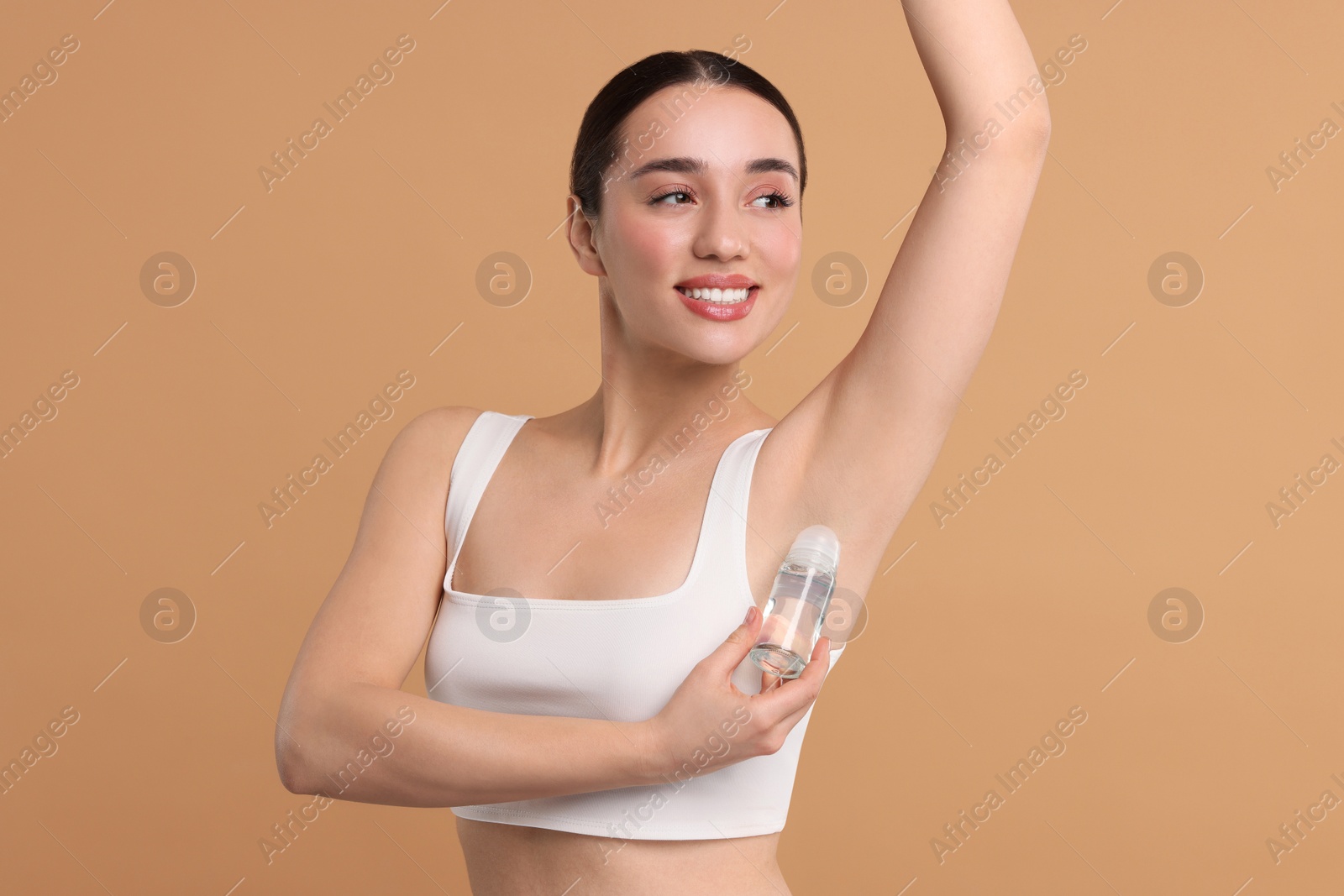 Photo of Beautiful woman applying deodorant on beige background