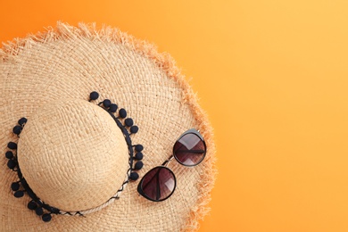 Stylish summer hat and sunglasses on color background, top view