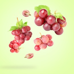 Image of Fresh grapes and leaves in air on light green background