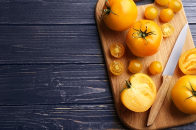 Photo of Ripe yellow tomatoes on blue wooden table, top view. Space for text