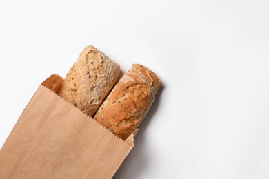 Paper bag with bread loaves on white background, top view. Space for text