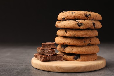 Photo of Stack of delicious chocolate chip cookies on grey table, closeup. Space for text
