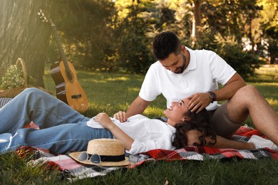 Lovely couple spending time together on picnic plaid in park