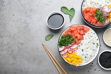 Photo of Delicious poke bowls with salmon and vegetables served on light grey table, flat lay. Space for text
