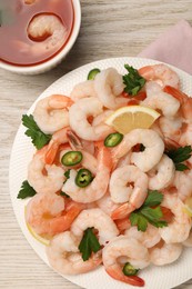 Tasty boiled shrimps with cocktail sauce, chili, parsley and lemon on light wooden table, flat lay