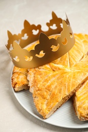 Traditional galette des Rois with paper crown on light grey marble table