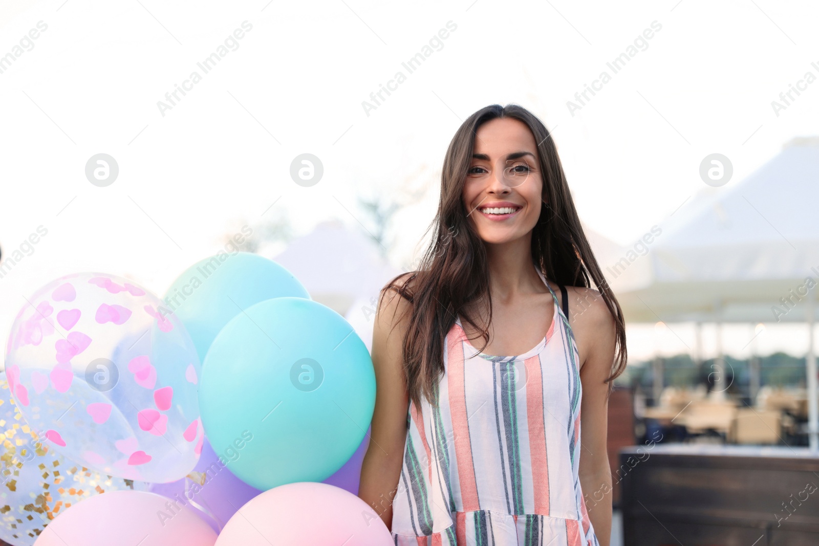 Photo of Beautiful young woman with color balloons on city street