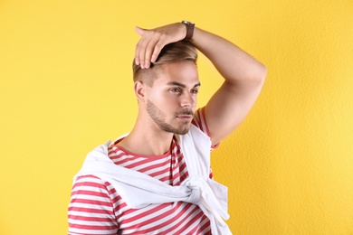 Young man with trendy hairstyle on color background