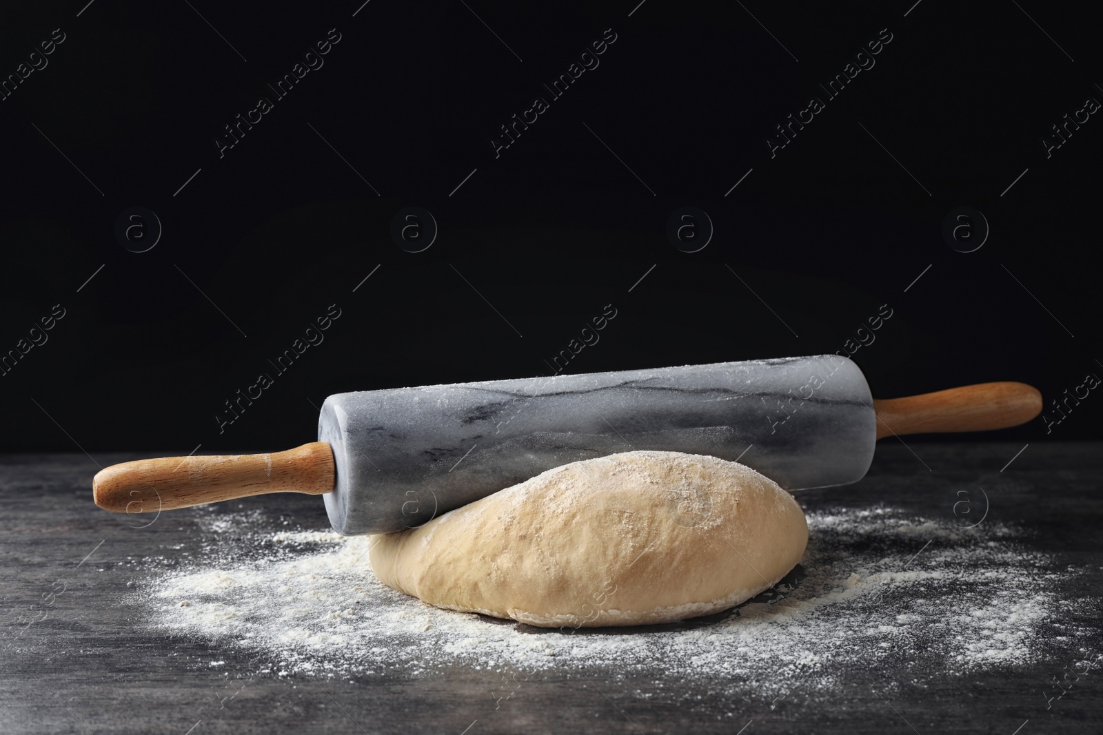 Photo of Raw wheat dough with flour and rolling pin on table