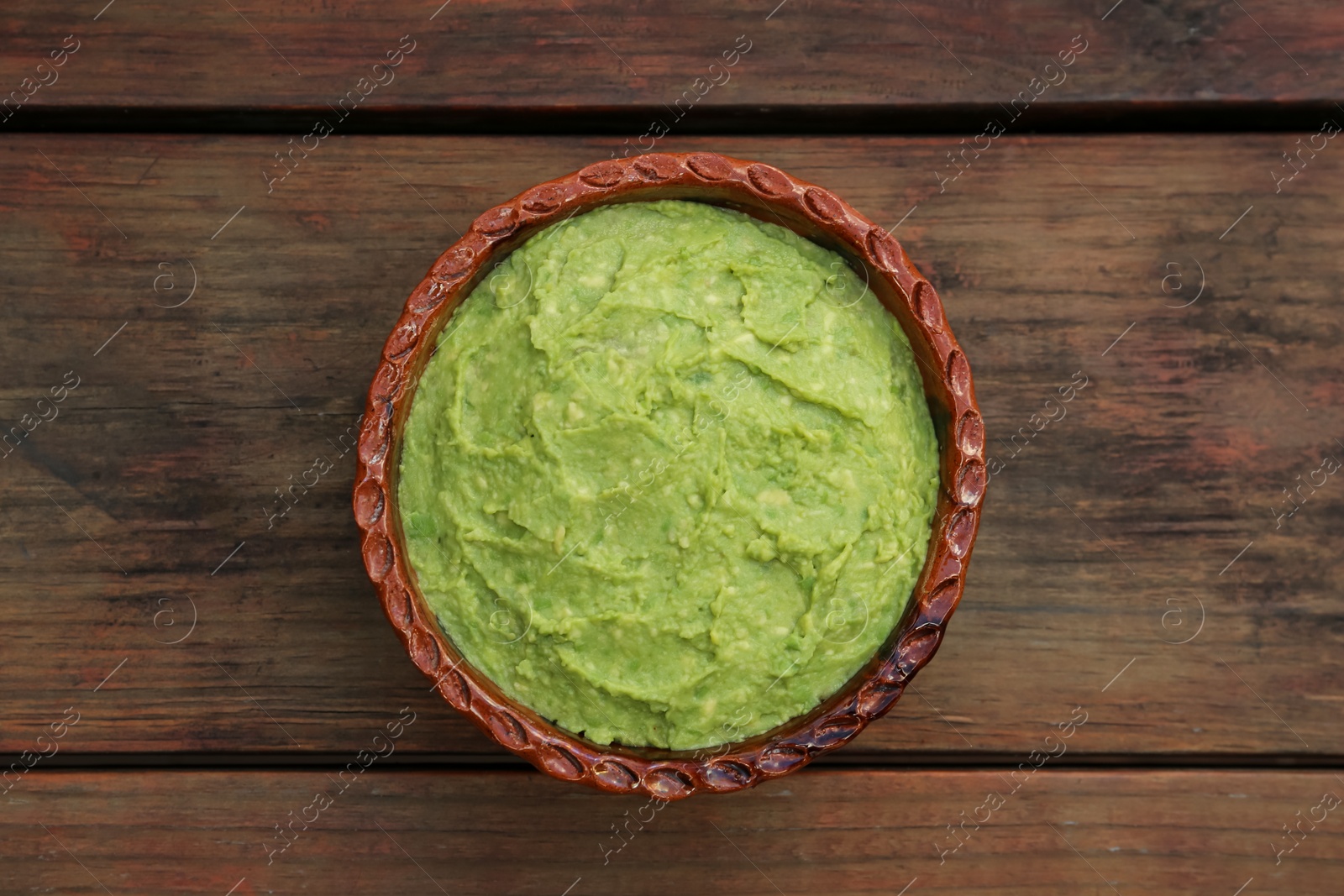 Photo of Delicious guacamole made of avocados on wooden table, top view