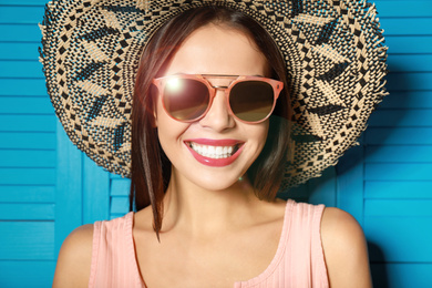 Image of Beautiful woman wearing sunglasses and hat near blue wooden folding screen