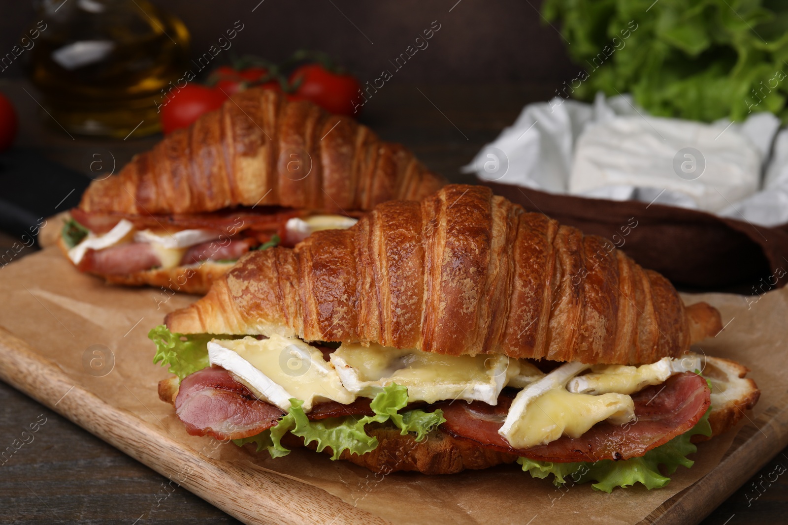 Photo of Tasty croissants with brie cheese, ham and bacon on table, closeup