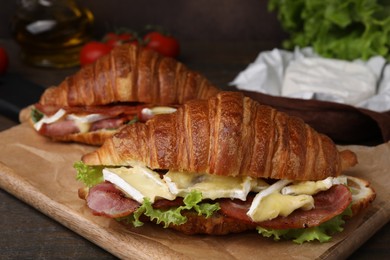 Photo of Tasty croissants with brie cheese, ham and bacon on table, closeup