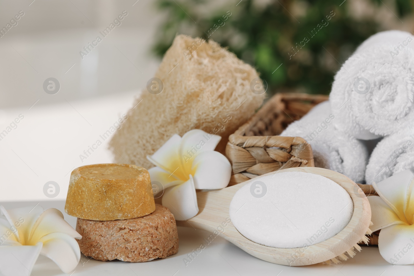 Photo of Composition with different spa products and plumeria flowers on white table, closeup