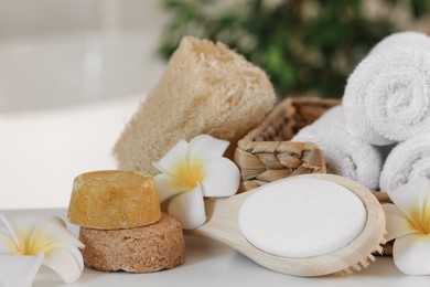 Photo of Composition with different spa products and plumeria flowers on white table, closeup