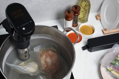 Thermal immersion circulator and vacuum packed meat in pot on table. Sous vide cooking