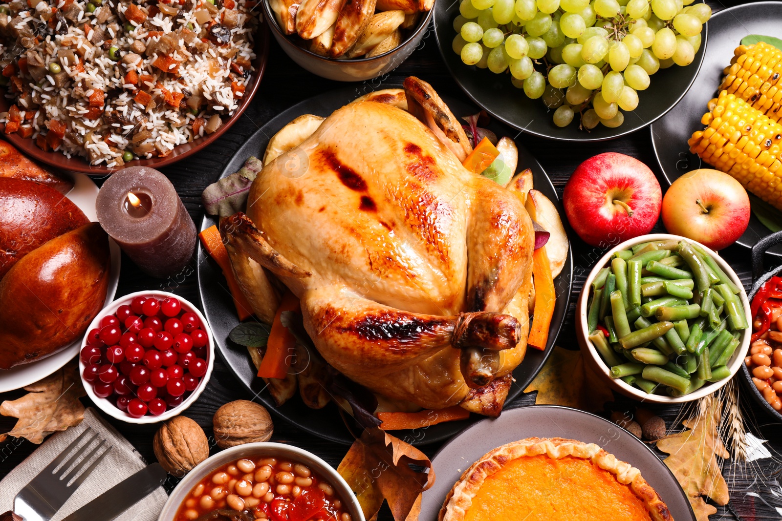 Photo of Traditional Thanksgiving day feast with delicious cooked turkey and other seasonal dishes served on black wooden table, flat lay