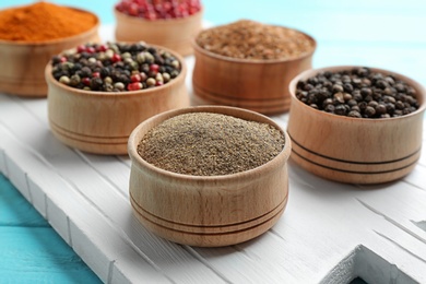 Bowls with different kinds of pepper on white wooden board