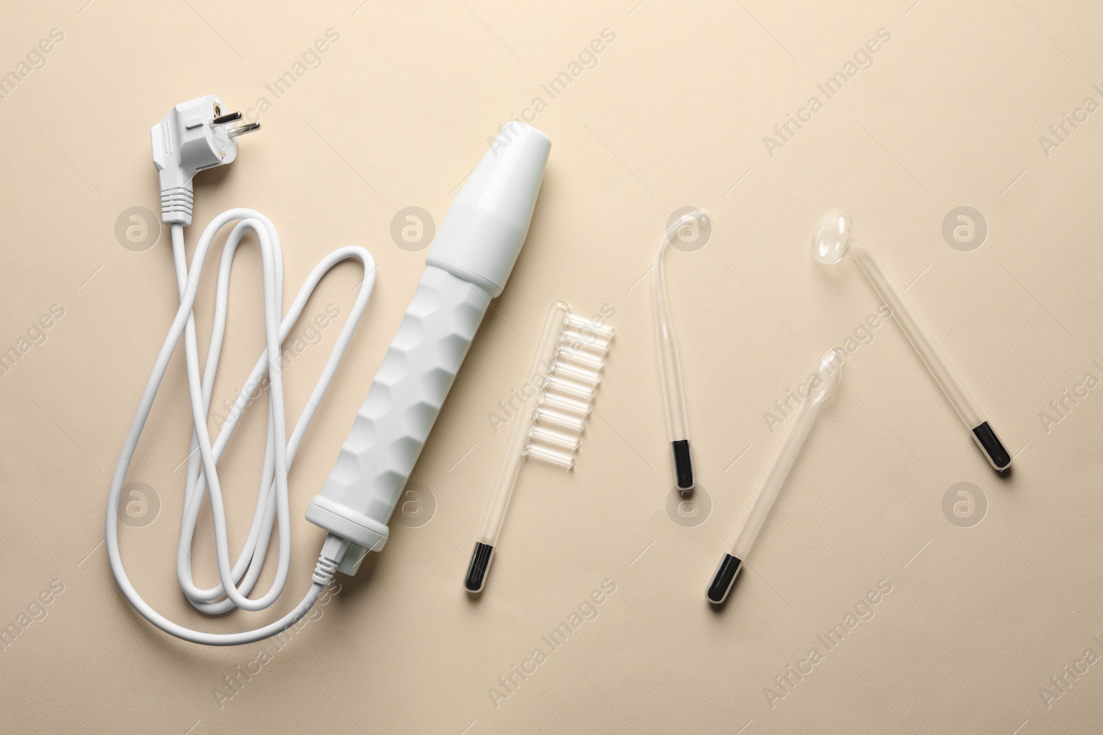 Photo of Darsonval with different nozzles on beige background, flat lay