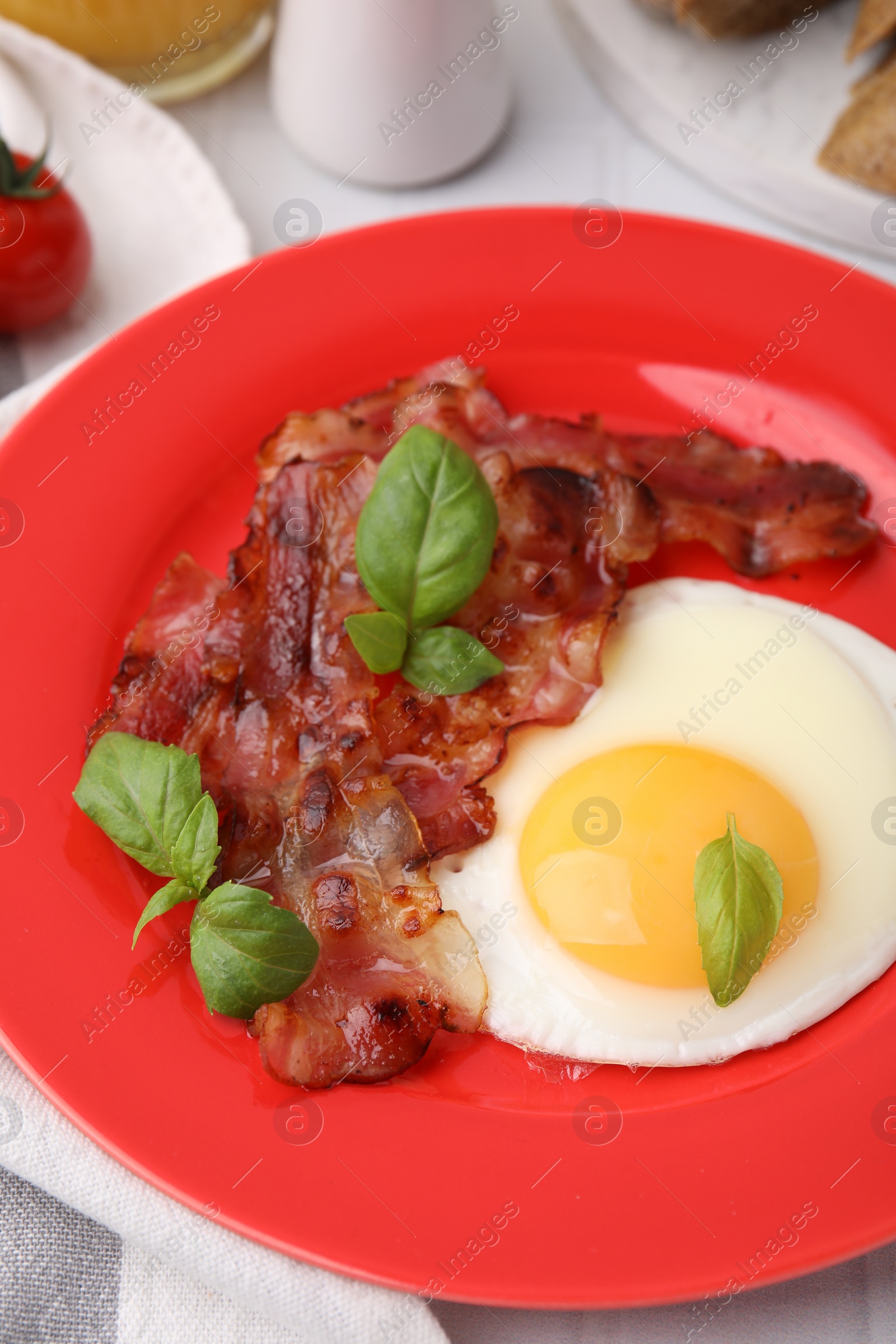 Photo of Fried egg, bacon and basil on table