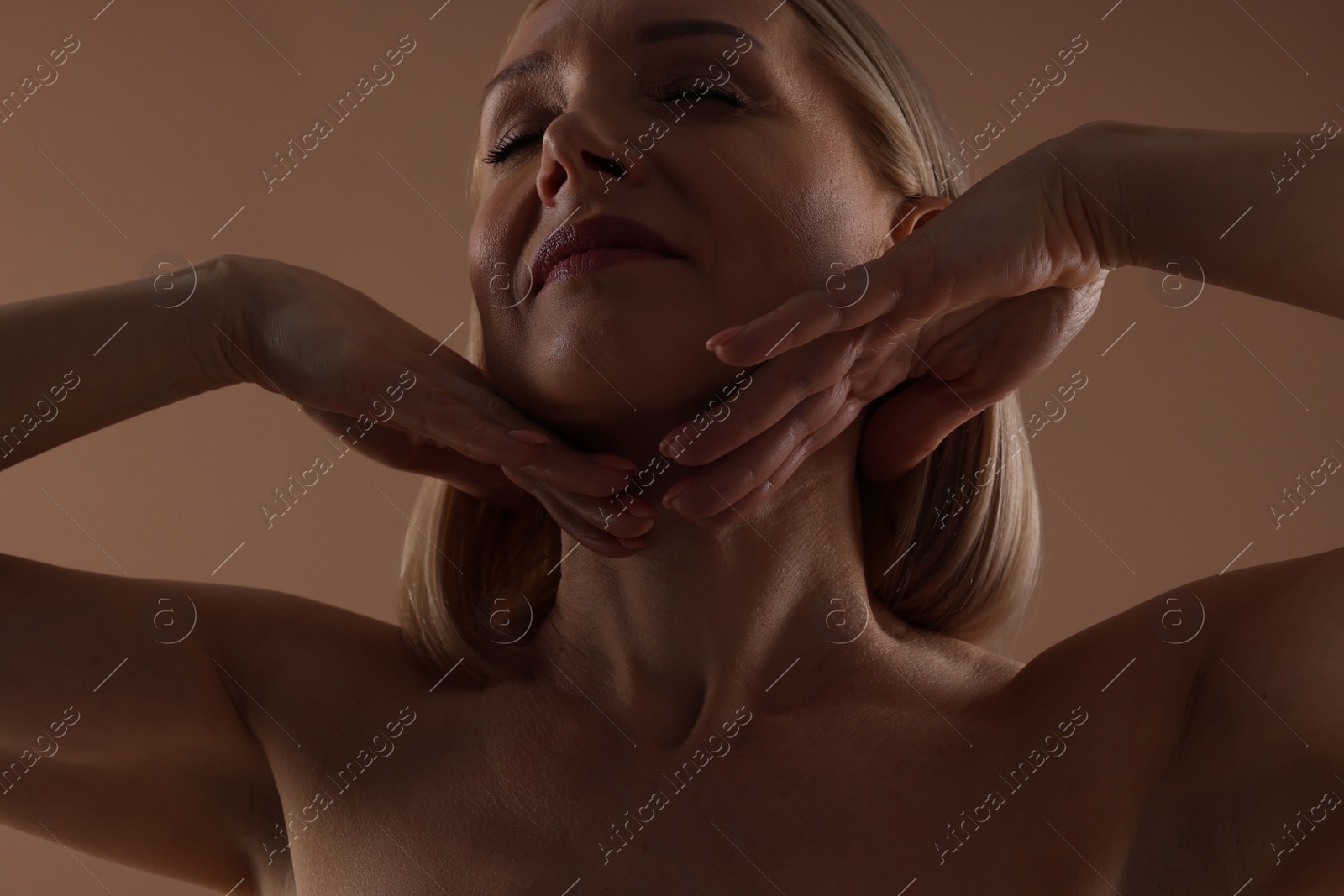 Photo of Beautiful woman touching her neck on beige background, closeup