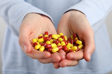 Woman holding many antibiotic pills, closeup. Medicinal treatment