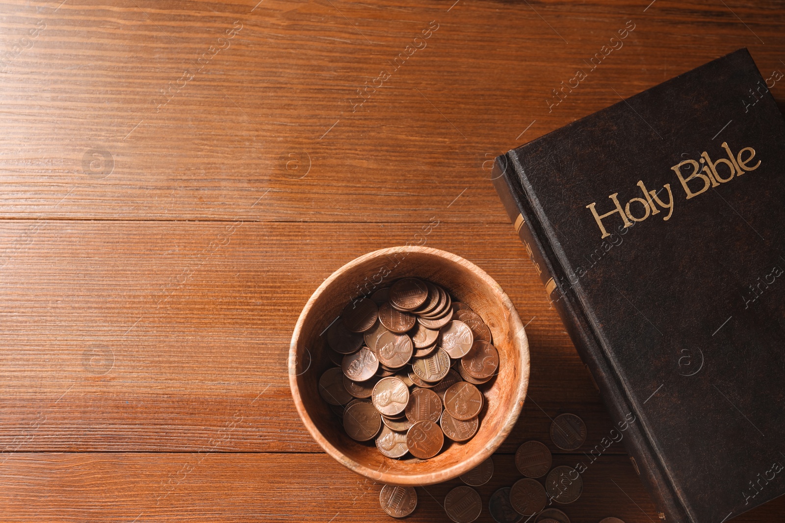 Photo of Donate and give concept. Coins in bowl and Bible on wooden table, flat lay. Space for text