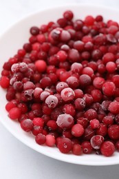 Photo of Frozen red cranberries in bowl on white table, closeup