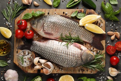 Photo of Fresh raw crucian carps and ingredients on grey table, flat lay. River fish