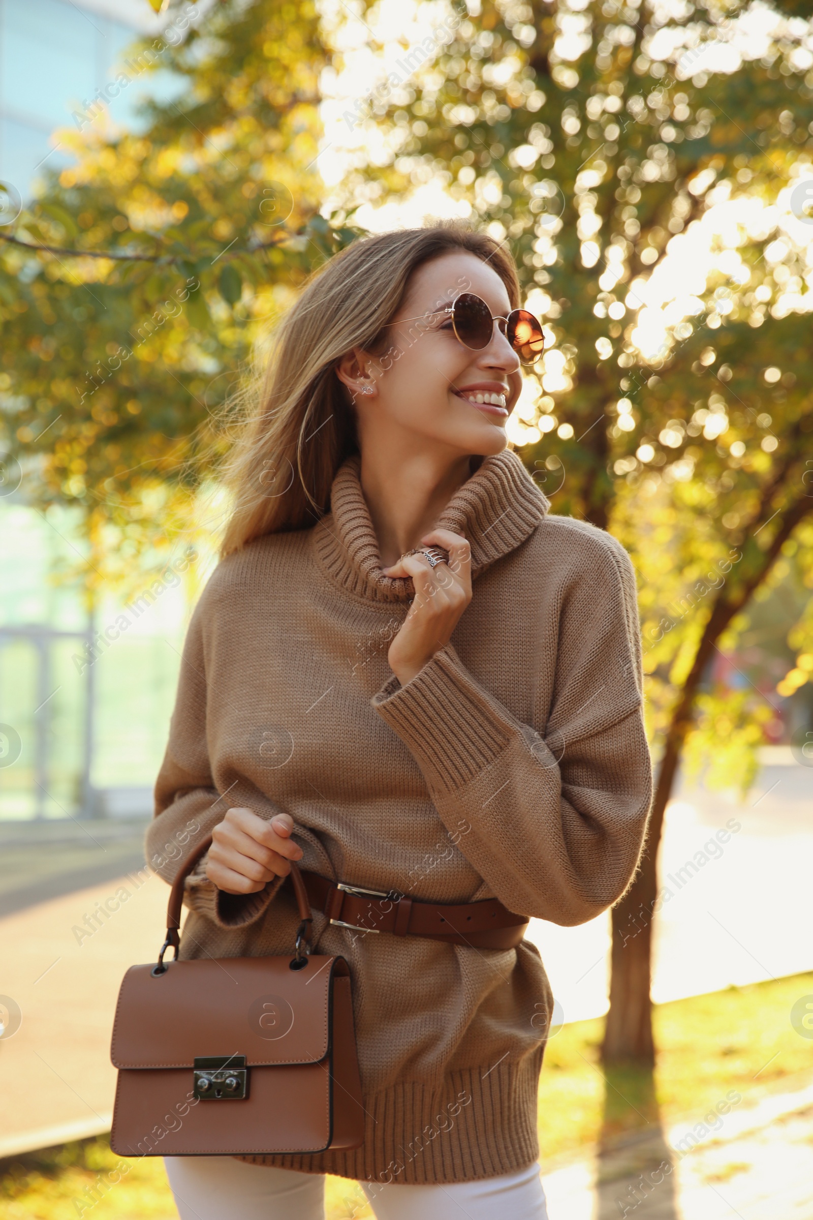 Photo of Beautiful young woman wearing stylish sweater in autumn park