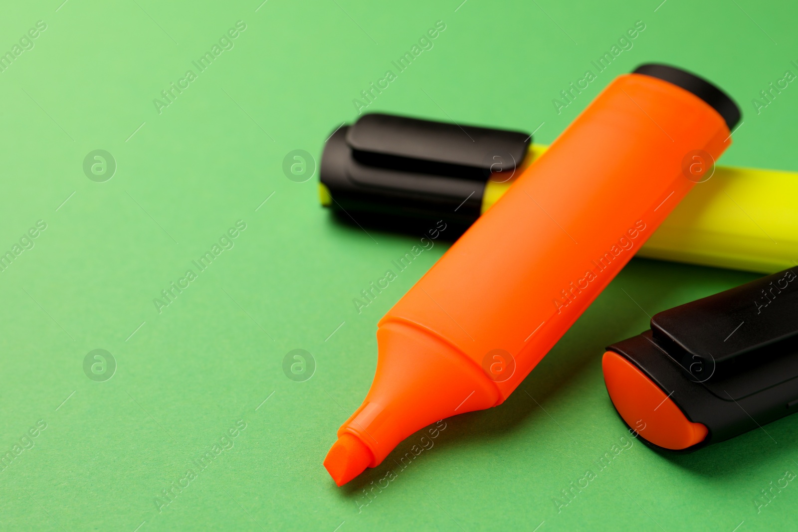 Photo of Bright color markers on green background, closeup. Space for text