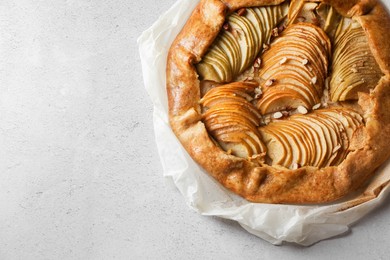 Photo of Delicious apple galette with pecans on light gray textured table, top view. Space for text