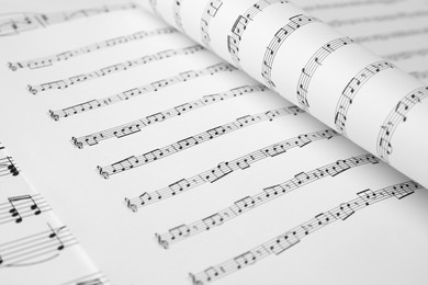 Photo of Sheets of paper with music notes as background, closeup