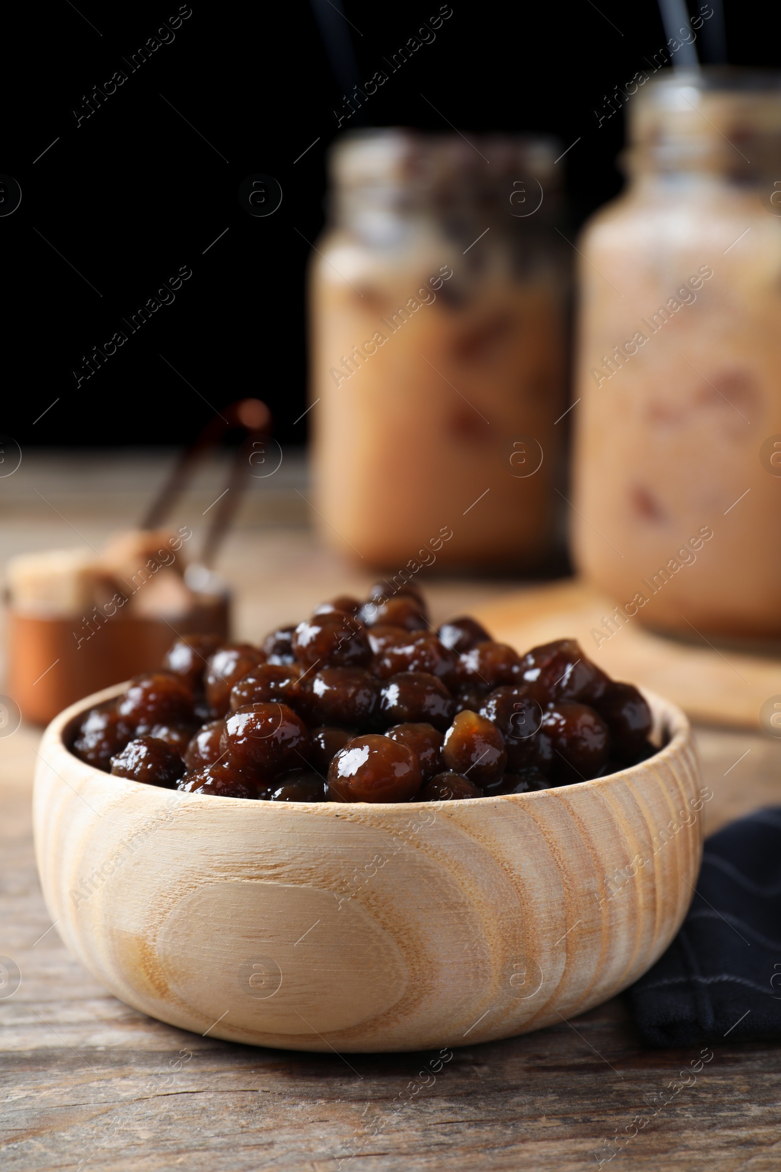 Photo of Tapioca balls for milk bubble tea in bowl on wooden table, closeup