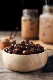 Photo of Tapioca balls for milk bubble tea in bowl on wooden table, closeup