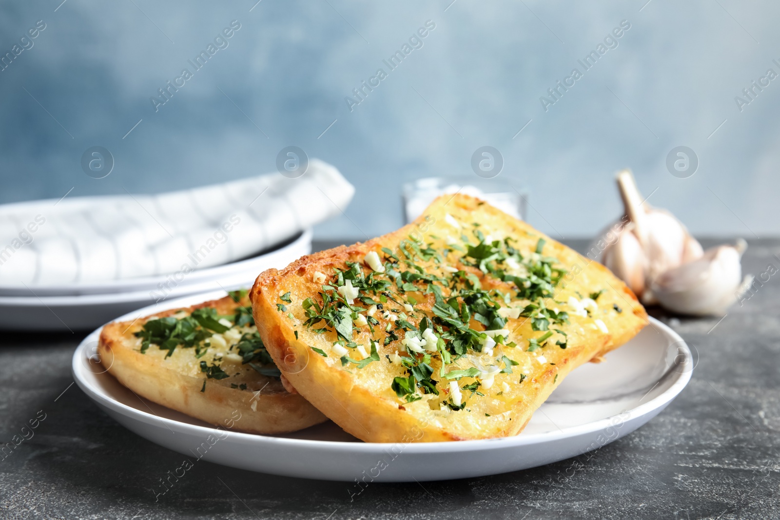 Photo of Plate with delicious homemade garlic bread on table