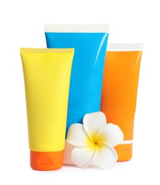 Tubes with sunscreen cream and flower on white background. Cosmetic products