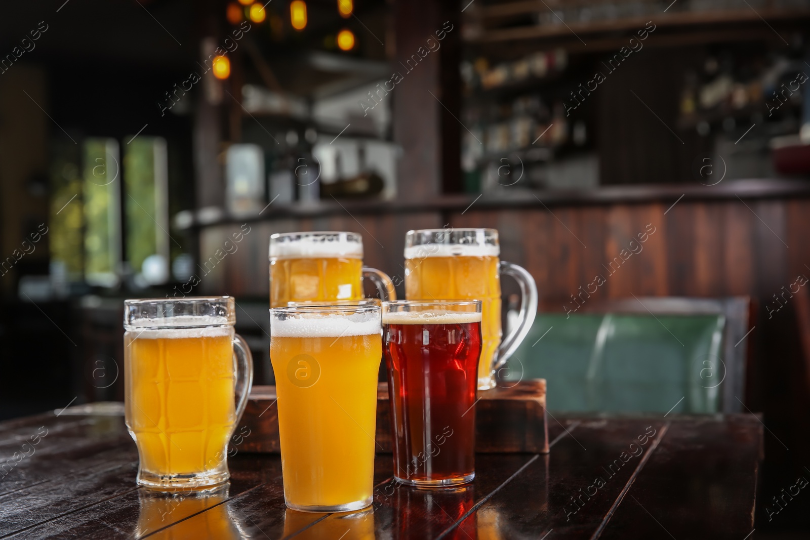 Photo of Glasses of tasty beer on wooden table in bar