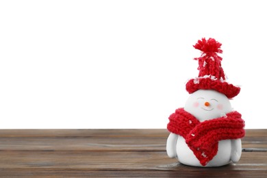 Cute decorative snowman in red hat and scarf on wooden table against white background, space for text