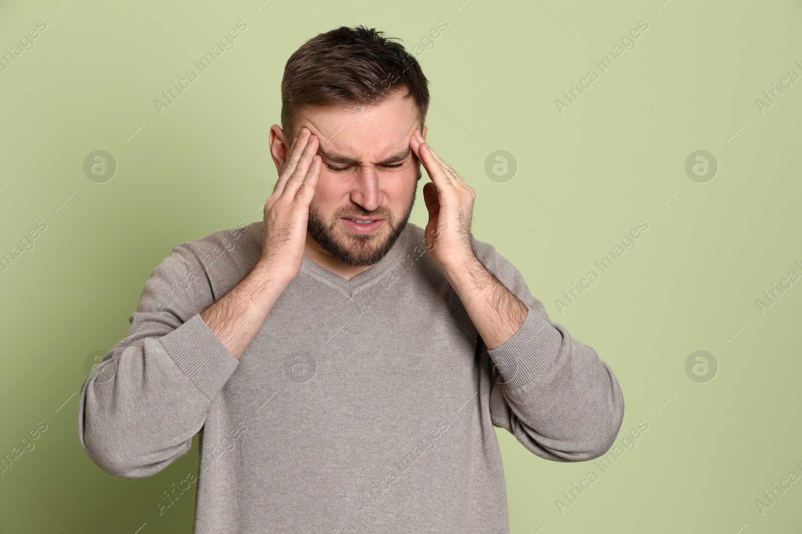 Photo of Man suffering from migraine on light green background