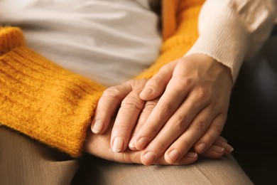 Photo of Young and elderly women holding hands together, closeup