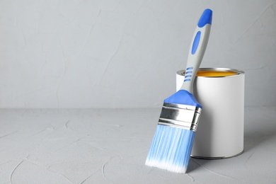 Photo of Can of paint and brush on grey table. Space for text