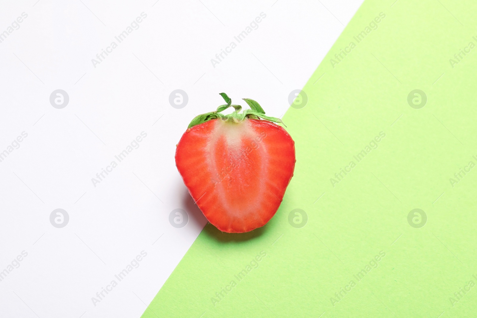 Photo of Half of ripe strawberry on color background, top view