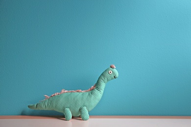 Photo of Abandoned toy dinosaur on table against color background. Time to visit child psychologist